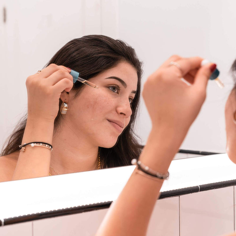 woman applying CBD Facial Oil on her face